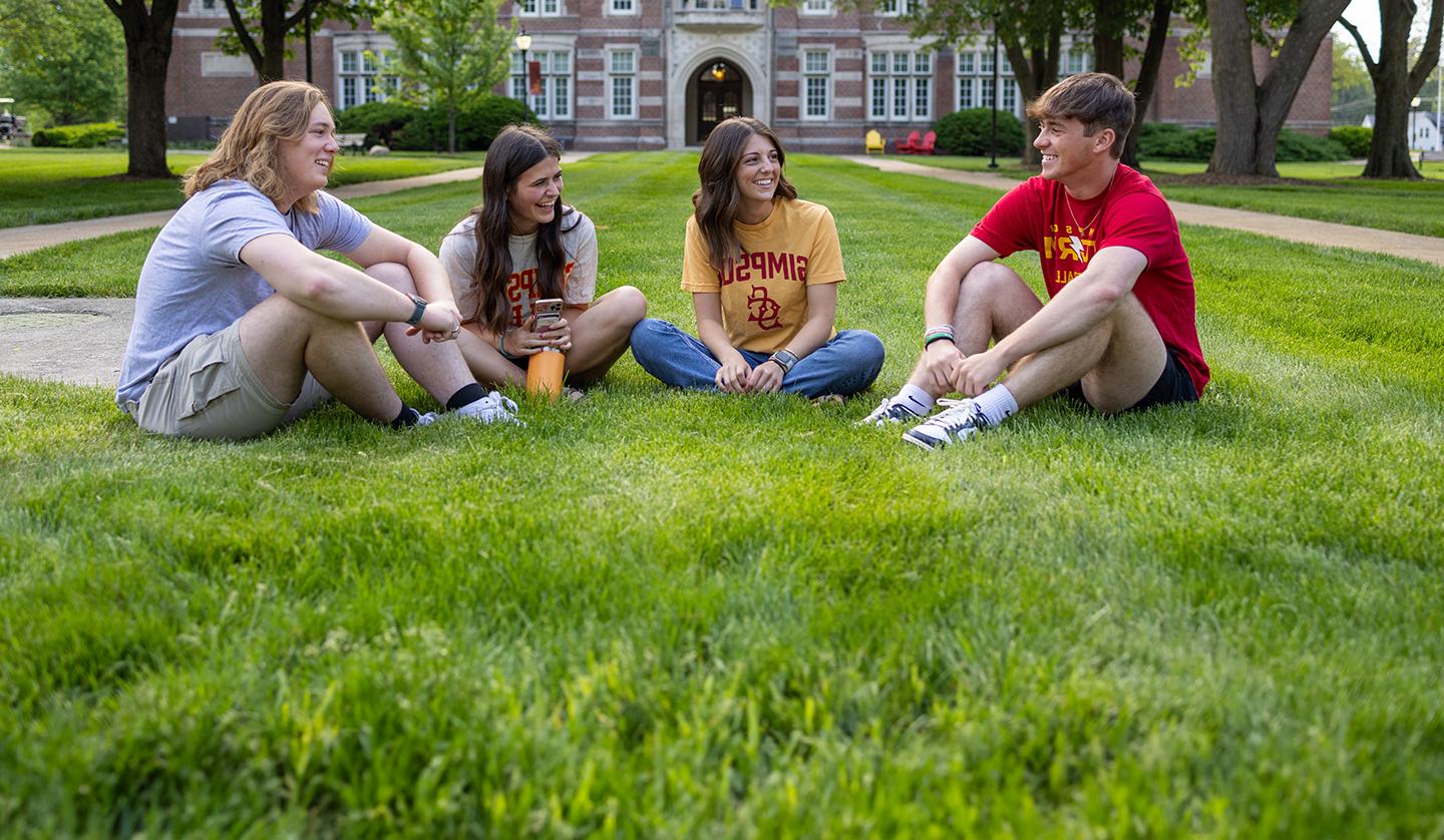 Students sitting in the quad laughing